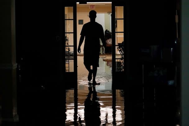 PHOTO: A resident's relative walks through the Peach Tree Village nursing home to collect family possessions from the flooded facility in Brandon, Miss., following a morning of torrential rains, Aug. 24, 2022. (Rogelio V. Solis/AP)