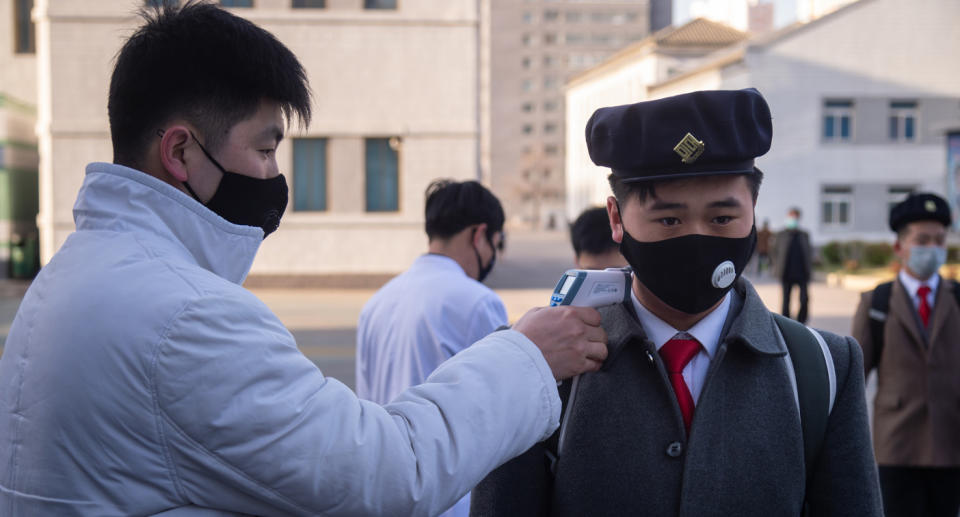 A student wearing a face mask undergoes a temperature check as he arrives for a lecture on preventative measures against the COVID-19 novel coronavirus at the Pyongyang University of Medicine. 