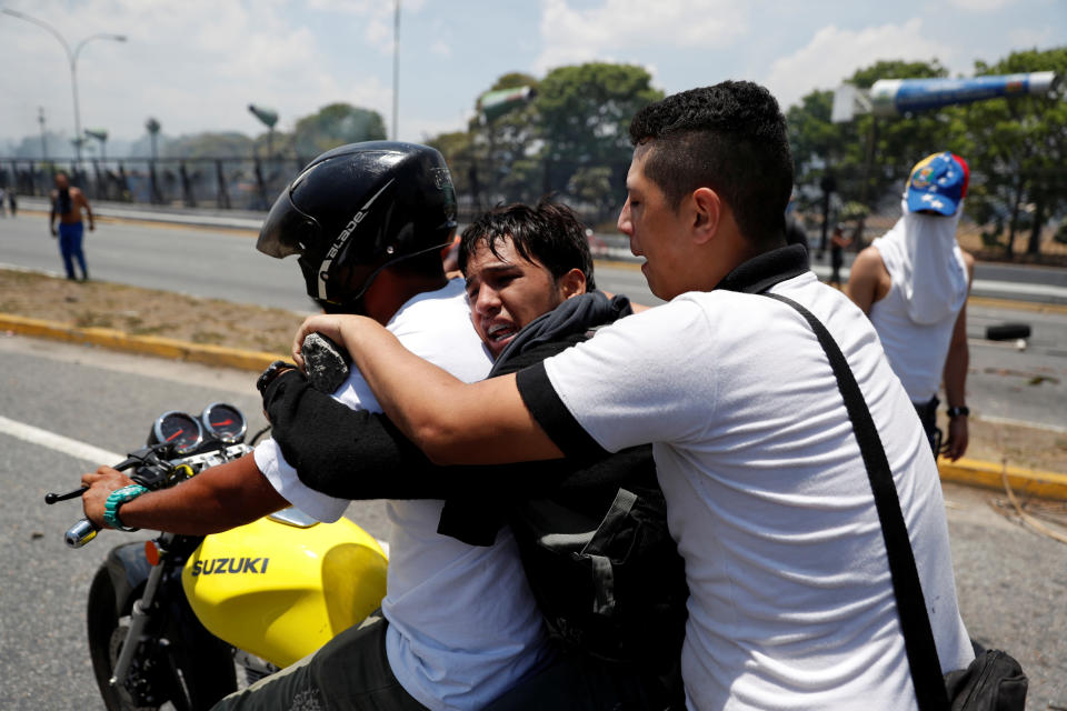 Opposition demonstrators help an injured fellow near the Generalisimo Francisco de Miranda Airbase “La Carlota” in Caracas