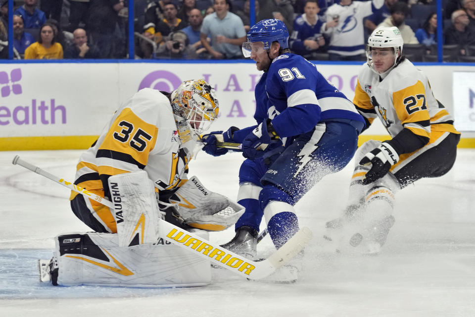 Pittsburgh Penguins goaltender Tristan Jarry (35) stops a shot by Tampa Bay Lightning center Steven Stamkos (91) during the second period of an NHL hockey game Thursday, Nov. 30, 2023, in Tampa, Fla. Defending for the Penguins is Ryan Graves (27). (AP Photo/Chris O'Meara)