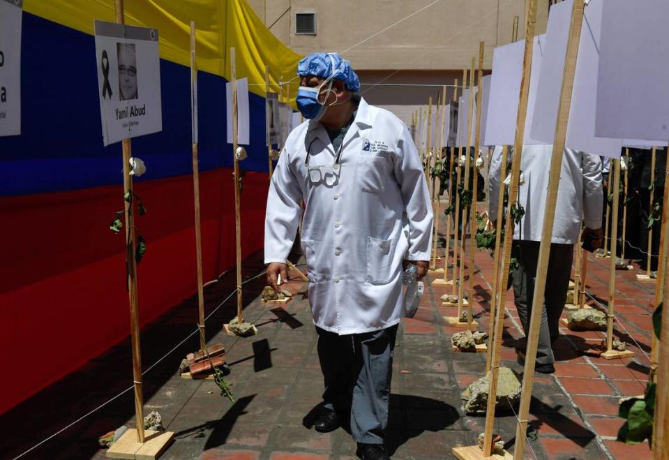 A healthcare worker walks past photos of doctors who died from COVID-19 at the Venezuelan Medical Federation in Caracas last year.