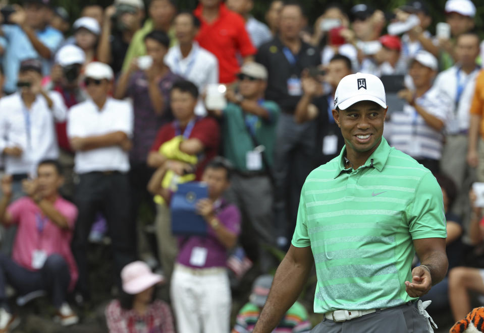 Tiger Woods of the United States smiles during an exhibition golf match against Rory Mcllory of Northern Ireland in Haikou, in southern China's island province Hainan, Monday, Oct. 28, 2013. (AP Photo/Vincent Yu)