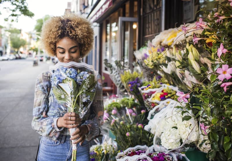 Smiling woman smelling hydrangeas outside flower shop