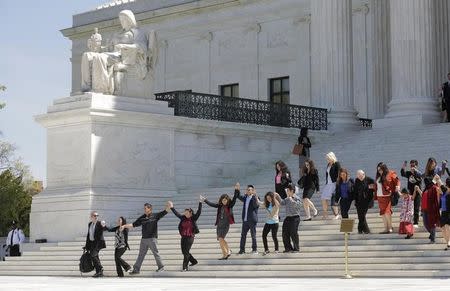 Immigration activists join hands after the U.S. Supreme Court heard arguments in a challenge by 26 states over the constitutionality of President Barack Obama's executive action to defer deportation of certain immigrant children and parents who are in the country illegally in Washington, April 18, 2016. REUTERS/Joshua Roberts