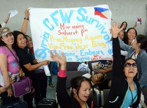 Philippine workers, who had been working in Syria, display a banner as they wait to be processed after disembarking from a plane chartered by the International Organization for Migration at the international airport in Manila