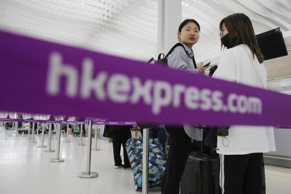 In this March 26, 2019 photo, passengers wait at the check-in counter of Hong Kong Express Airways at the Hong Kong International Airport. Cathay Pacific Airways is acquiring Hong Kong-based budget airline HK Express. Cathay said Wednesday, March 27, 2019, it will pay 4.93 billion Hong Kong dollars ($628 million) for HK Express. It said the acquisition will retain its identity as a separate brand and be operated as a low-cost carrier. (AP Photo/Kin Cheung)