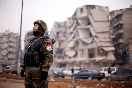A member of forces loyal to Syria's President Bashar al-Assad stands near damaged buildings in Aleppo's Salaheddine district, Syria December 16, 2016. REUTERS/Omar Sanadiki