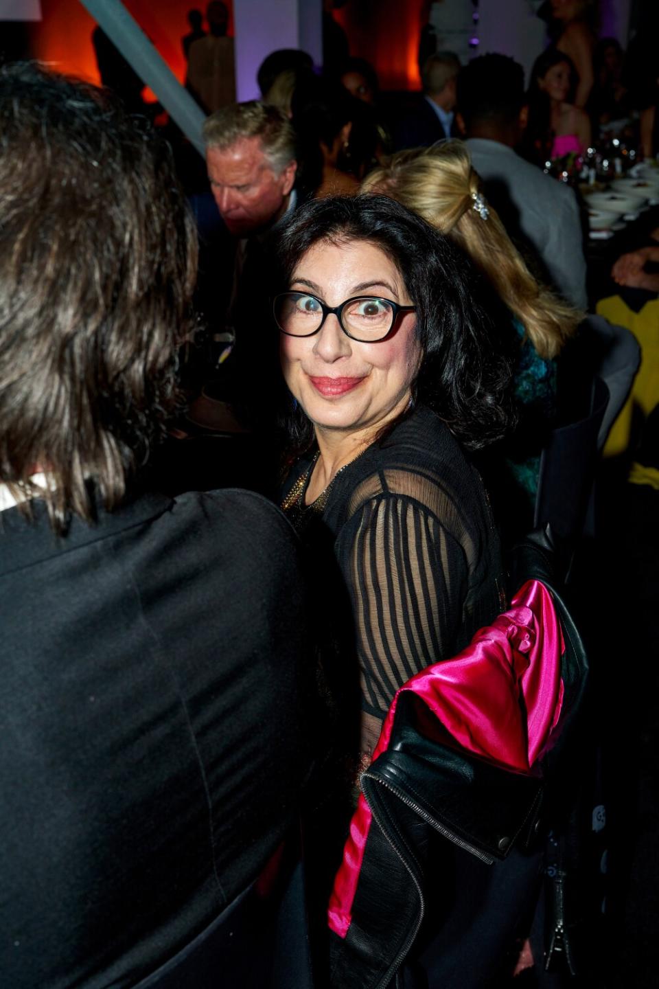 A woman with black eye glasses smiles and looks at the camera