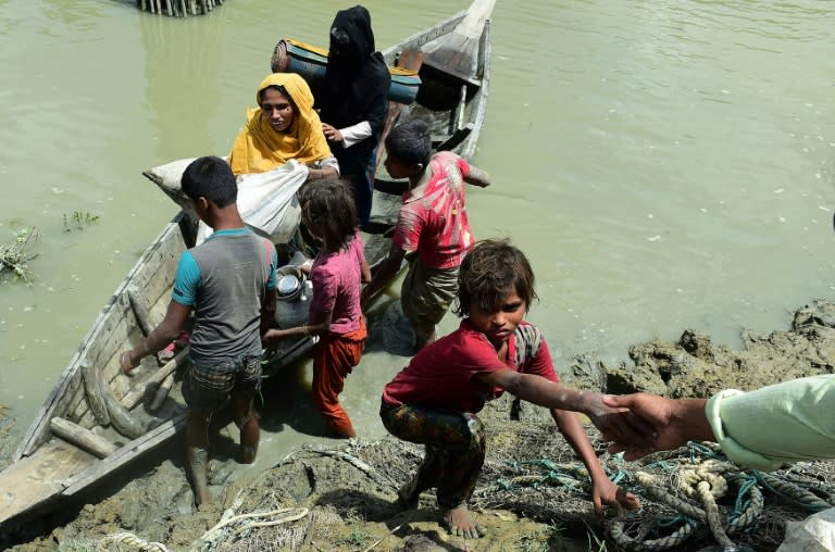 Local Bangladeshis help Rohingya Muslim refugees to disembark from a boat on the Bangladeshi side of Naf river near the Bangladeshi town of Teknaf on September 11, 2017