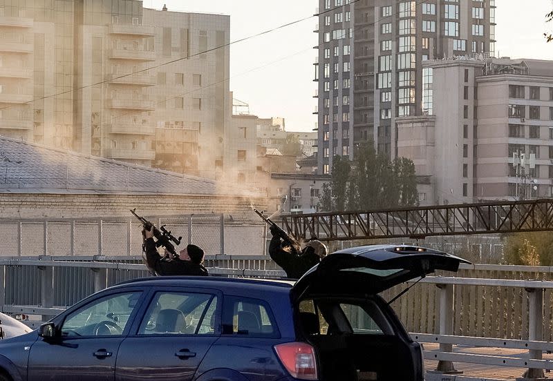 Police officers shoot at a drone during a Russian drone strike in Kyiv