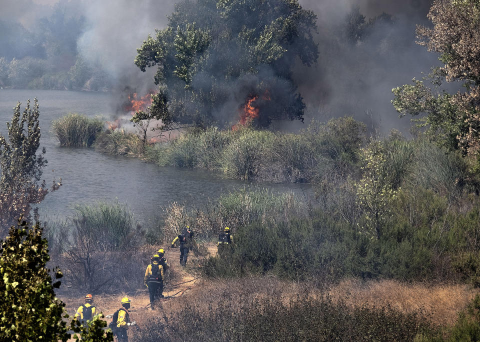 Los Angeles Fire Department firefighters make their way into the Sepulveda Basin to fight a brush fire in the Sherman Oaks area of Los Angeles, Sunday, Sept. 6, 2020. In Southern California, crews scrambled to douse several fires that popped up. The largest was a blaze in the foothills of Yucaipa east of Los Angeles that prompted evacuation orders for eastern portions of the city of 54,000 along with several mountain communities. (AP Photo/Richard Vogel)