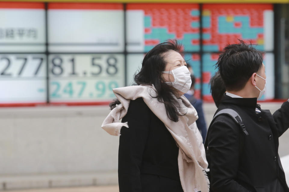 People walk by an electronic stock board of a securities firm in Tokyo, Monday, Dec. 6, 2021. Shares were mixed in Asia on Monday after troubled Chinese property developer Evergrande warned late Friday it may run out of money. (AP Photo/Koji Sasahara)