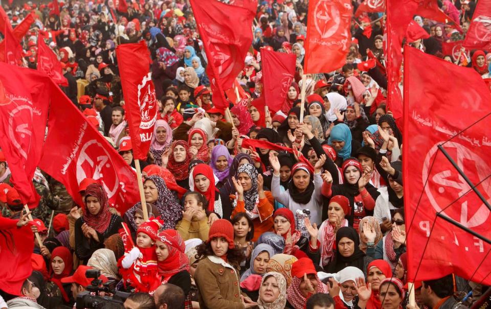 Palestinian women sing while waving red flags at a rally marking the 43rd anniversary of the leftist Popular Front for the Liberation of Palestine (PFLP), in Gaza City , Saturday, Dec. 11, 2010. Arabic on the flags reads 'Popular Front for the Liberation of Palestine (PFLP).'
