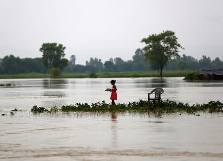 A girl carrying dishes walks along a flooded area in Janakpur, Nepal August 13, 2017. REUTERS/Navesh Chitrakar