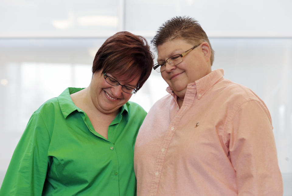 April DeBoer, left, and Jayne Rowse, react during a news conference in Ferndale, Mich., Friday, March 21, 2014. A federal judge has struck down Michigan's ban on gay marriage Friday the latest in a series of decisions overturning similar laws across the U.S. The two nurses who've been partners for eight years claimed the ban violated their rights under the U.S. Constitution. (AP Photo/Paul Sancya)