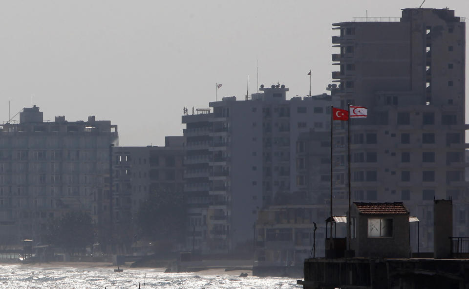 FILE - In this Friday, Jan. 17, 2014 file photo, Turkish and Turkish Cypriot breakaway flags are seen on a military guard post in front of the deserted hotels in an area used by the Turkish military in the Turkish occupied area, in the abandoned coastal city of Varosha in Famagusta, southeast Cyprus. The man who hopes to be the next leader of the breakaway Turkish state in northern Cyprus, Ersin Tatar says ongoing tensions over drilling for oil and gas would fade if Greek Cypriots drop their objections and agree to divvy up the country’s territorial waters and drilling rights. (AP Photo/Petros Karadjias, File)