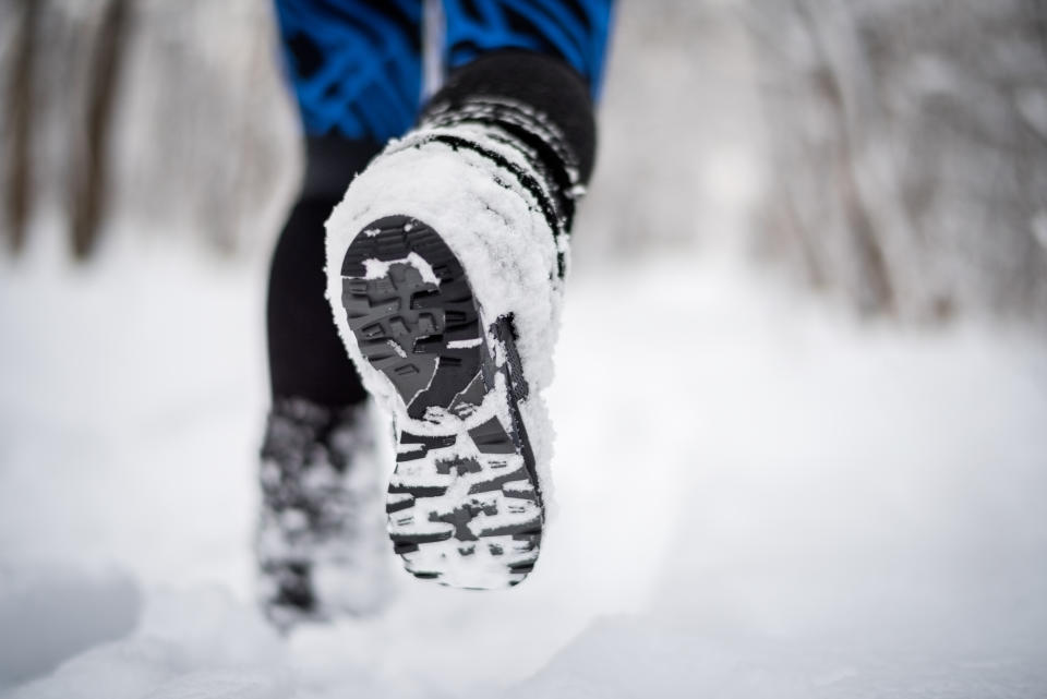 These heated socks lets you say goodbye to cold feet for good. Shoe sole of a person walking on the path covered with snow.