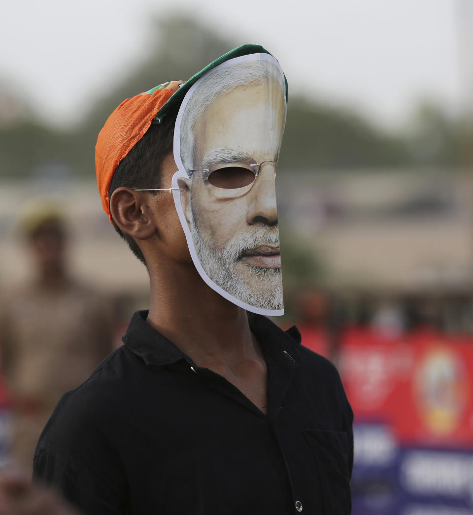 FILE- In this Thursday, May 9, 2019 file photo, a supporter of India's ruling Bharatiya Janata Party (BJP) wears a mask of Indian prime minister Narendra Modi and waits for his arrival during an election campaign rally in Prayagraj, India. The final phase of India’s marathon general election will be held on Sunday, May 19. The first of the election’s seven staggered phases was held on April 11. Vote counting is scheduled to start on May 23. India has 900 million eligible voters. (AP Photo/Rajesh Kumar Singh, File)