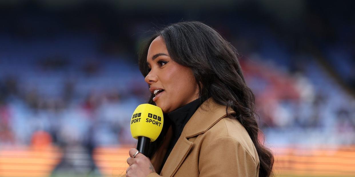alex scott holds a bbc sport microphone as she presents live coverage of a football game