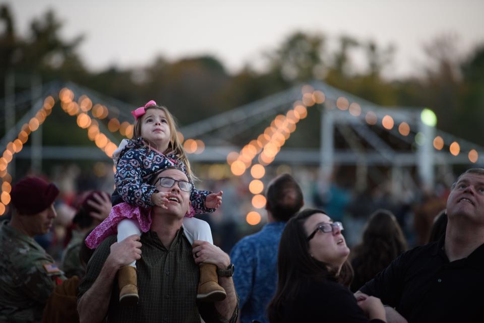 Mike Snowden and his daughter, Taylor, 3, look up and watch the Golden Knights parachute team jump from a plane during the Fort Bragg Family of the Year and Tree Lighting ceremony on Friday, Dec. 3, 2021.