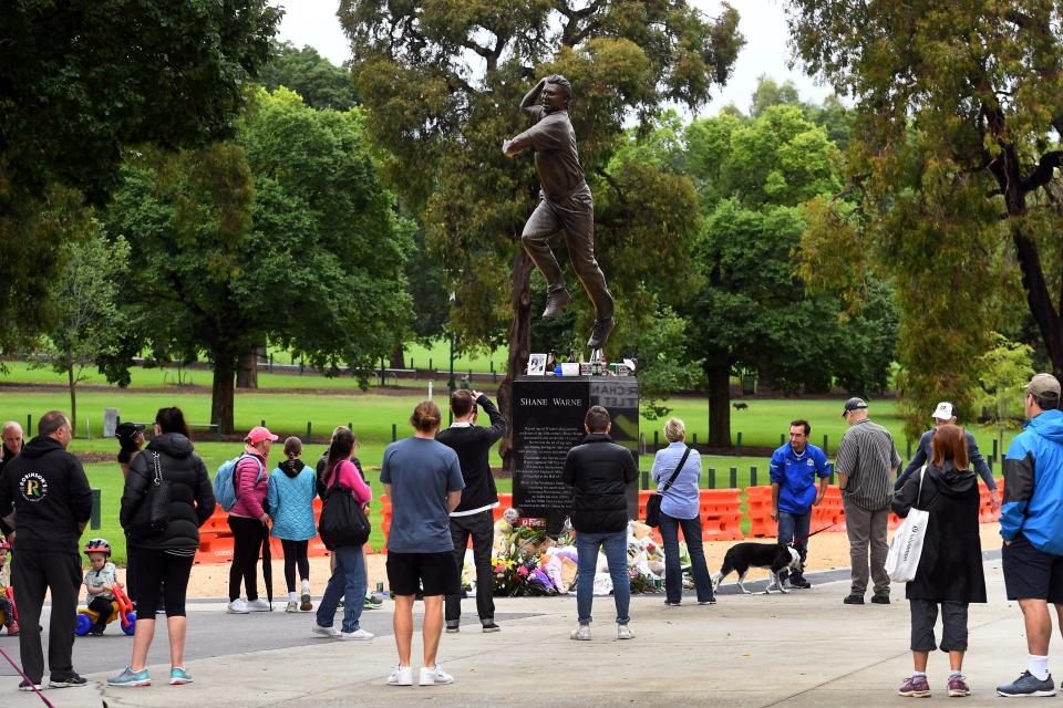 People, pictured here paying their respects at a statue of former Shane Warne outside the MCG.