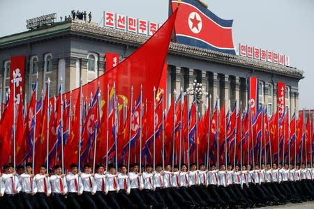 Men carry flags in front of the stand with North Korean leader Kim Jong Un and other high ranking officials during a military parade marking the 105th birth anniversary of the country's founding father, Kim Il Sung, in Pyongyang April 15, 2017. REUTERS/Damir Sagolj