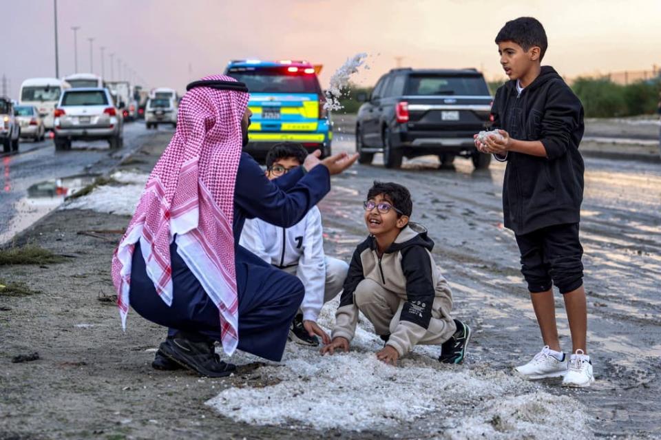 Un homme et des enfants à Oum al-Haïman après la tempête de grêle au Koweït le 27 décembre 2022 - YASSER AL-ZAYYAT / AFP