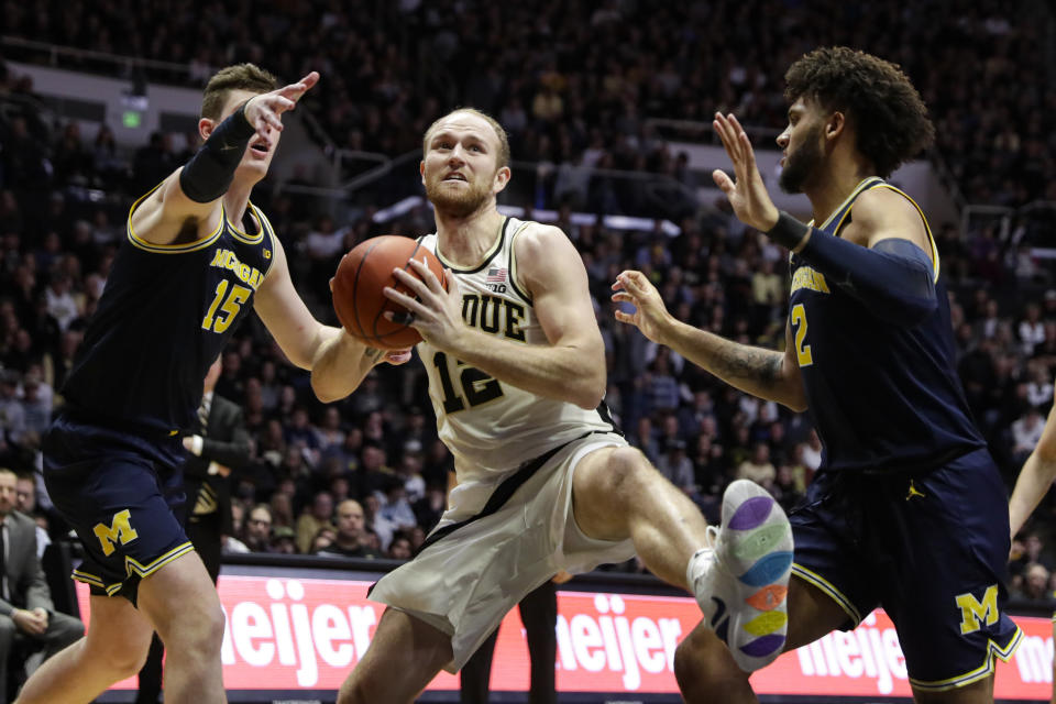 Purdue forward Evan Boudreaux (12) grabs a rebound between Michigan center Jon Teske (15) and forward Isaiah Livers (2) during the second half of an NCAA college basketball game in West Lafayette, Ind., Saturday, Feb. 22, 2020. (AP Photo/Michael Conroy)