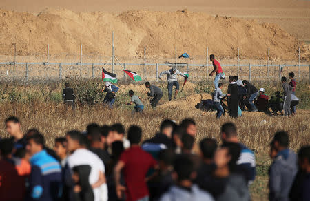 Palestinians take cover for cover from Israeli gunfire during a protest, at the Israel-Gaza border fence in the southern Gaza Strip May 3, 2019. REUTERS/Ibraheem Abu Mustafa