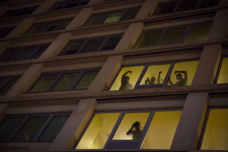 People watch from windows at a passing demonstration calling for social, economic and racial justice, in Manhattan, April 29, 2015. REUTERS/Andrew Kelly