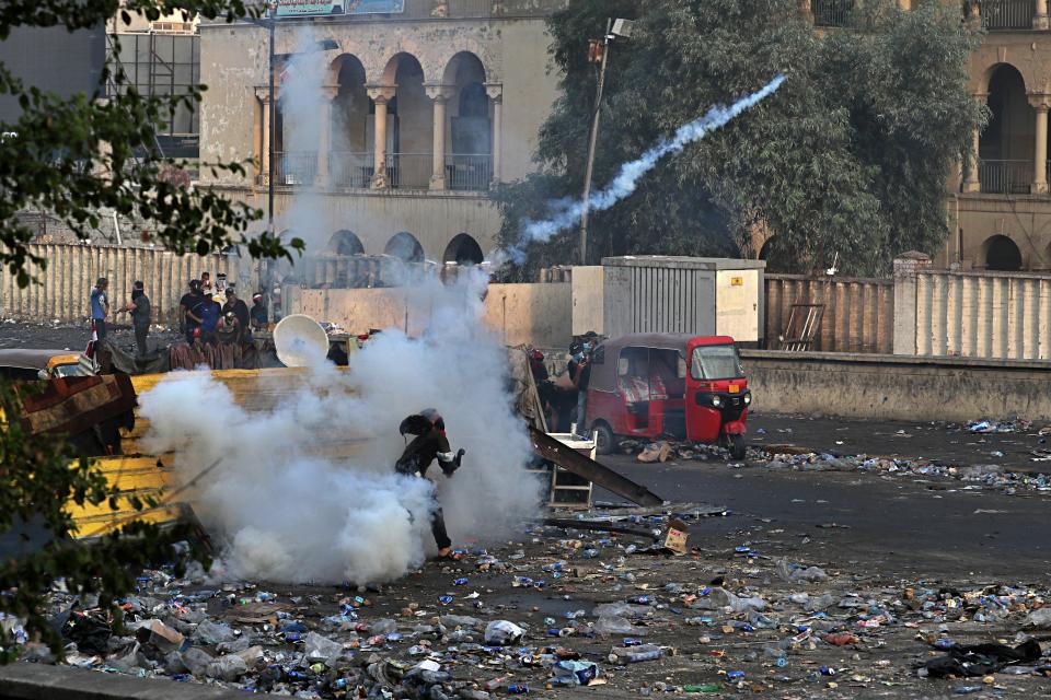 Anti-government protesters take cover while Iraqi Security forces fire tear gas and close the bridge leading to the Green Zone, during a demonstration in Baghdad, Iraq, Sunday, Oct. 27, 2019. Protests have resumed in Iraq after a wave of anti-government protests earlier this month were violently put down. (Photo: Khalid Mohammed/AP)