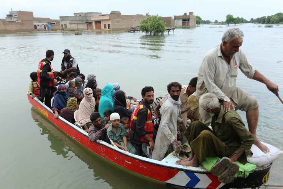 Residents arrive in a boat to a safer place after being evacuated following heavy monsoon rainfall in the flood affected area of Rajanpur district in Punjab province on August 24, 2022. - Record monsoon rains were causing a 