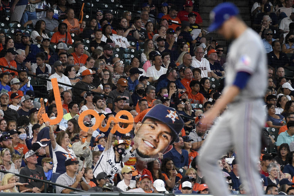 Fans hold up a sign in the likeness of Houston Astros' Jose Altuve after Altuve's single as Texas Rangers relief pitcher Brett Martin, right, walks back up the mound during the fourth inning of a baseball game, Sunday, July 25, 2021, in Houston. (AP Photo/Eric Christian Smith)