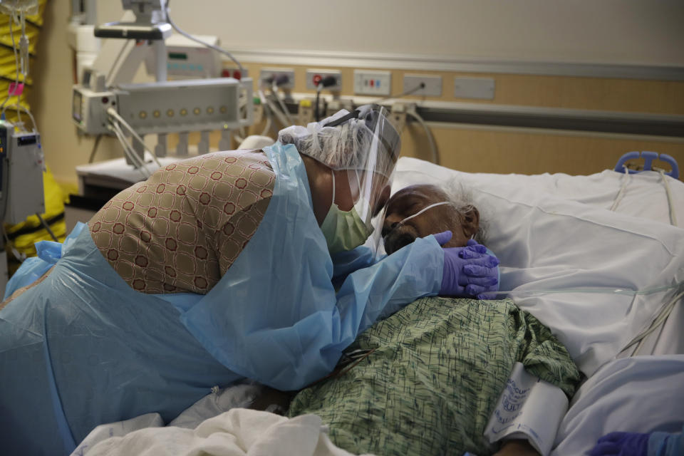 FILE - In this July 31, 2020, file photo, Romelia Navarro, 64, weeps while hugging her husband, Antonio, in his final moments in a COVID-19 unit at St. Jude Medical Center in Fullerton, Calif. The U.S. death toll from COVID-19 has almost topped 500,000 — a number so staggering that a top health researchers says it is hard to imagine an American who hasn't lost a relative or doesn't know someone who died. (AP Photo/Jae C. Hong, File)