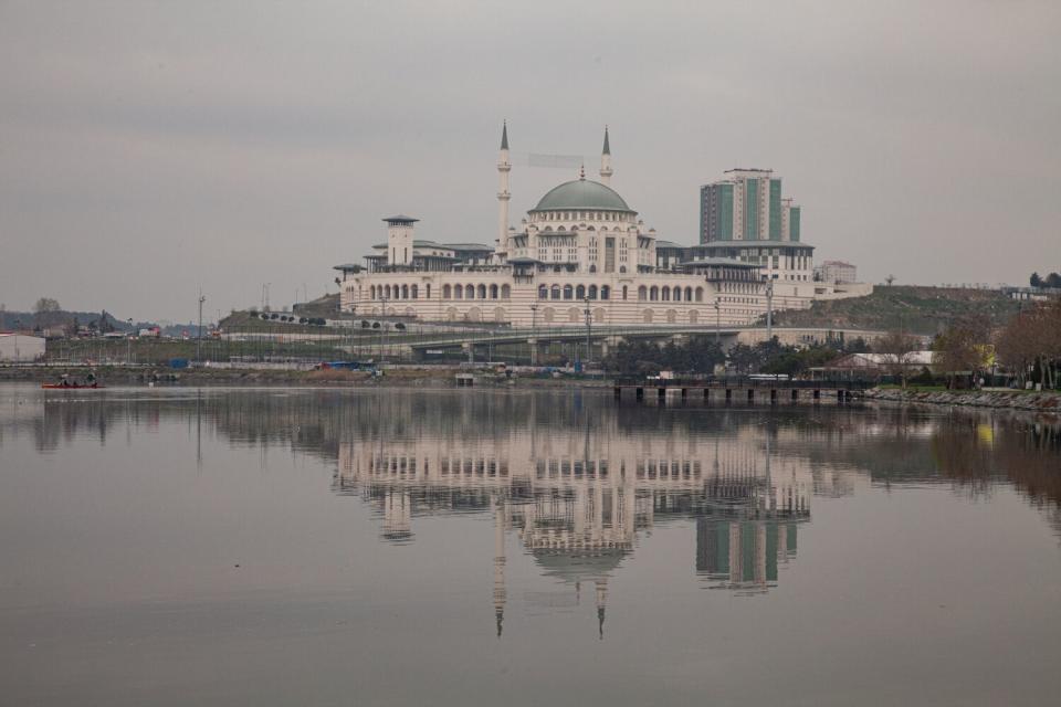 A view of a lake and a sprawling white building with a blue dome and minarets