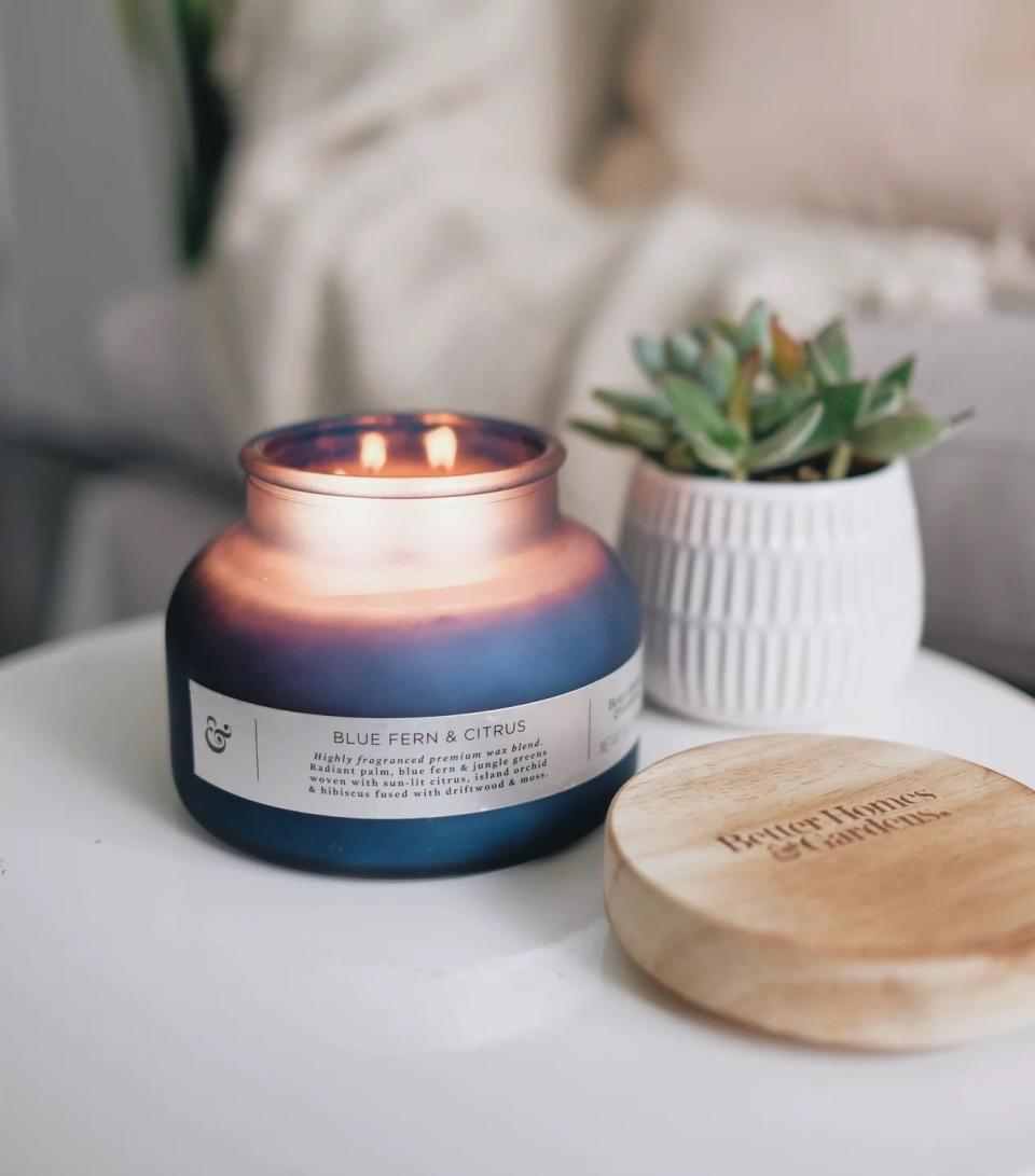 blue fern and citrus candle lit in a blue votive on a table