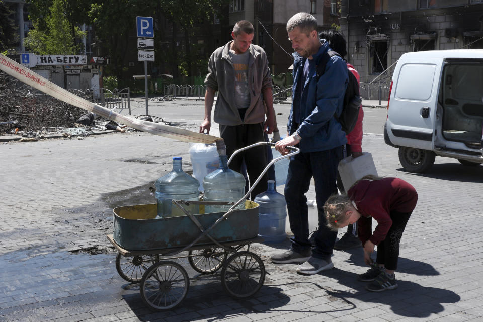 Local residents fil bottles with drinking water brought by Donetsk People Republic Emergency Situations Ministry in Mariupol, in territory under the government of the Donetsk People's Republic, eastern Ukraine, Thursday, May 12, 2022. (AP Photo)