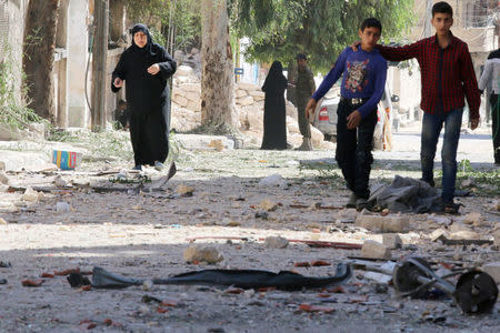 People walk on the rubble of damaged buildings at a site hit overnight by an air strike in the rebel-held area of Seif al-Dawla neighbourhood of Aleppo, Syria, September 30, 2016. REUTERS/Abdalrhman Ismail