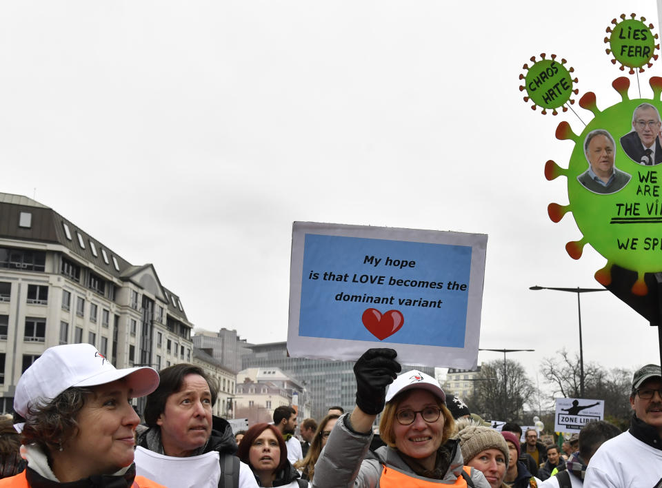 A protestor holds up a sign during a demonstration against COVID-19 measures in Brussels, Sunday, Jan. 23, 2022. Demonstrators gathered in the Belgian capital to protest what they regard as overly extreme measures by the government to fight the COVID-19 pandemic, including a vaccine pass regulating access to certain places and activities and possible compulsory vaccines.(AP Photo/Geert Vanden Wijngaert)