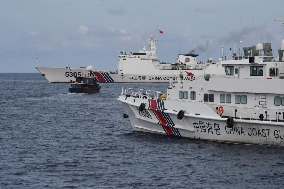 File Chinese coast guard ships (L and R) corralling a Philippine civilian boat chartered by the Philippine navy to deliver supplies to Philippine navy ship BRP Sierra Madre (AFP via Getty Images)