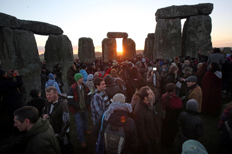 AMESBURY, ENGLAND - DECEMBER 21:  People gather to watch the sunrise as druids, pagans and revelers celebrate the winter solstice at Stonehenge on December 21, 2012 in Wiltshire, England. (Photo by Matt Cardy/Getty Images)