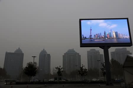 A electric screen showing Shanghai Pudong financial area in a clear day is seen amid heavy smog in Zhengzhou, Henan province, China, December 9, 2015. REUTERS/Stringer