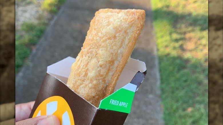 Hand holding McDonald's fried apple pie in carton