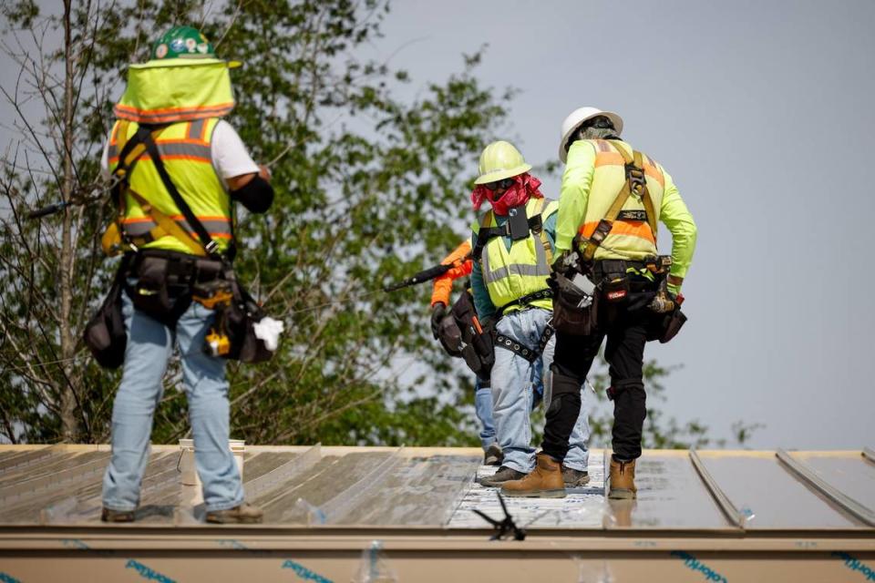 At a construction site in Ballantyne, two workers are tethered to a safety line while working on a roof. But one worker, on the far right, is not.