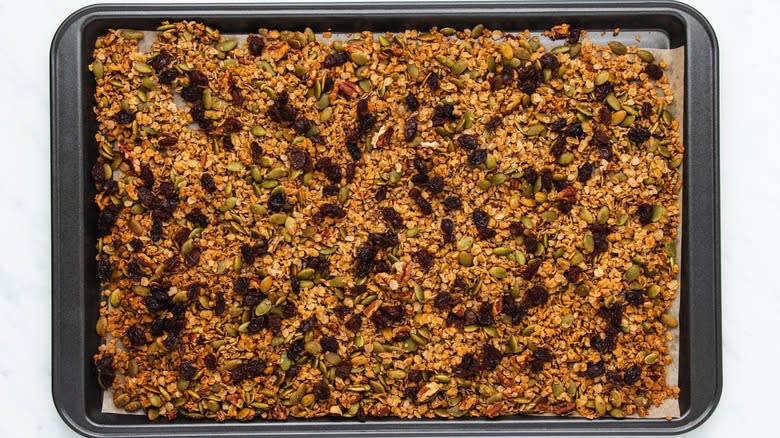 Pumpkin seed granola with raisins on baking sheet