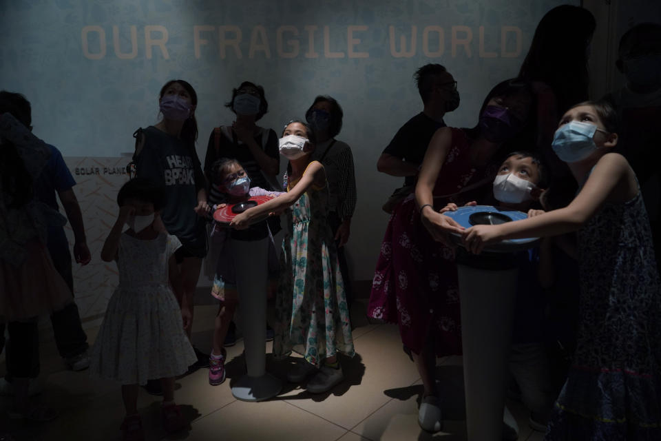 Visitors wearing face masks to prevent the spread of coronavirus, control the mock solar energy planes in the Hong Kong Science Museum, Wednesday, May 19, 2021. (AP Photo/Kin Cheung)