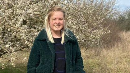 Lily Lucas smiling in front of a white blossom tree