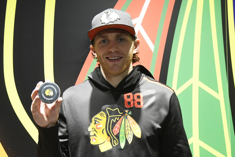Chicago Blackhawks right wing Patrick Kane (88) poses with the puck after getting his 1,0000th point on an assist against the Winnipeg Jets after an NHL hockey game Sunday, Jan. 19, 2020, in Chicago. (AP Photo/David Banks)