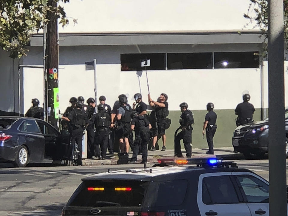 <p>Police officers use a mirror to see inside a Trader Joe’s store in the Silver Lake neighborhood of Los Angeles on Saturday. Police believe a man involved in the standoff with officers shot his grandmother and girlfriend before firing at officers during a pursuit, then crashing outside the supermarket and running inside the store. (Photo: Christian Dunlop via AP) </p>