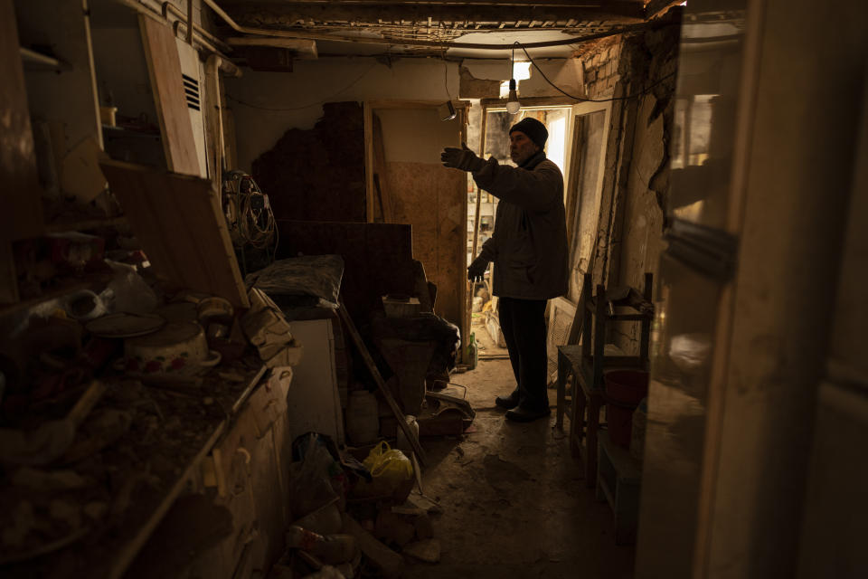 Oleksandr Luzhan gestures inside his mother's damaged home in Kupiansk, Ukraine, Monday, Feb. 20, 2023. Luzhan picked up insulation kits, containing wooden boards and other items, supplied by an aid group called HEKS/EPER Swiss Church Aid and said to increase indoor temperatures in battered homes by at least 5 degrees to seal his mother's house(AP Photo/Vadim Ghirda)